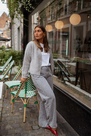 Gilet court à col rond gris porté par une femme, vue de face, vitrine, chaises vertes