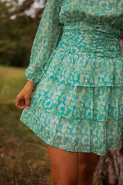 Robe fluide à motifs argentés portée par une femme, vue rapprochée, jupe superposée, taille smockée