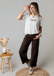Pantalon coupe barrel en sergé porté par une femme, vue de trois-quarts, main sur la tête