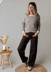 Pull rayé enrichi en laine porté par une femme, silhouette entière, tabouret, pantalon marron