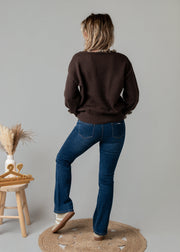 Pull col V léopard porté par une femme, vue de dos, jean flare, tabouret