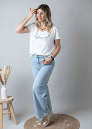 Jean large taille haute stretch porté par une femme, vue de trois-quarts, main dans les cheveux