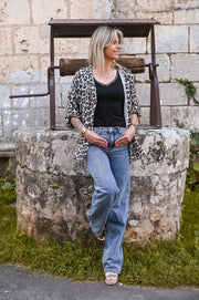 Chemise léopard en gaze portée par une femme, silhouette entière, puits en pierre, jean