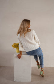 Gilet à boutons fleuris écru porté par une femme, vue de dos, cheveux longs, jean, cube blanc