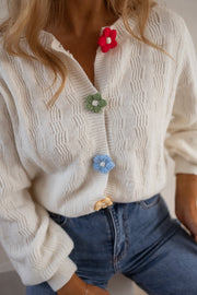 Gilet à boutons fleuris écru porté par une femme, gros plan des boutons fleurs et de la maille