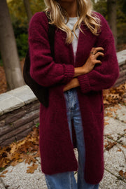 Gilet long à poches bordeaux porté par une femme, vue rapprochée, bras croisés, maille bordeaux