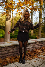 Gilet rayé col rond marron porté par une femme, vue de face, muret en pierre, bottines noires