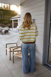 Gilet rayé doux boutonné porté par une femme, vue de dos, terrasse, chaise en bois