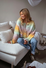 Gilet en maille tie-dye porté par une femme, vue rapprochée, mains dans les cheveux, boutons