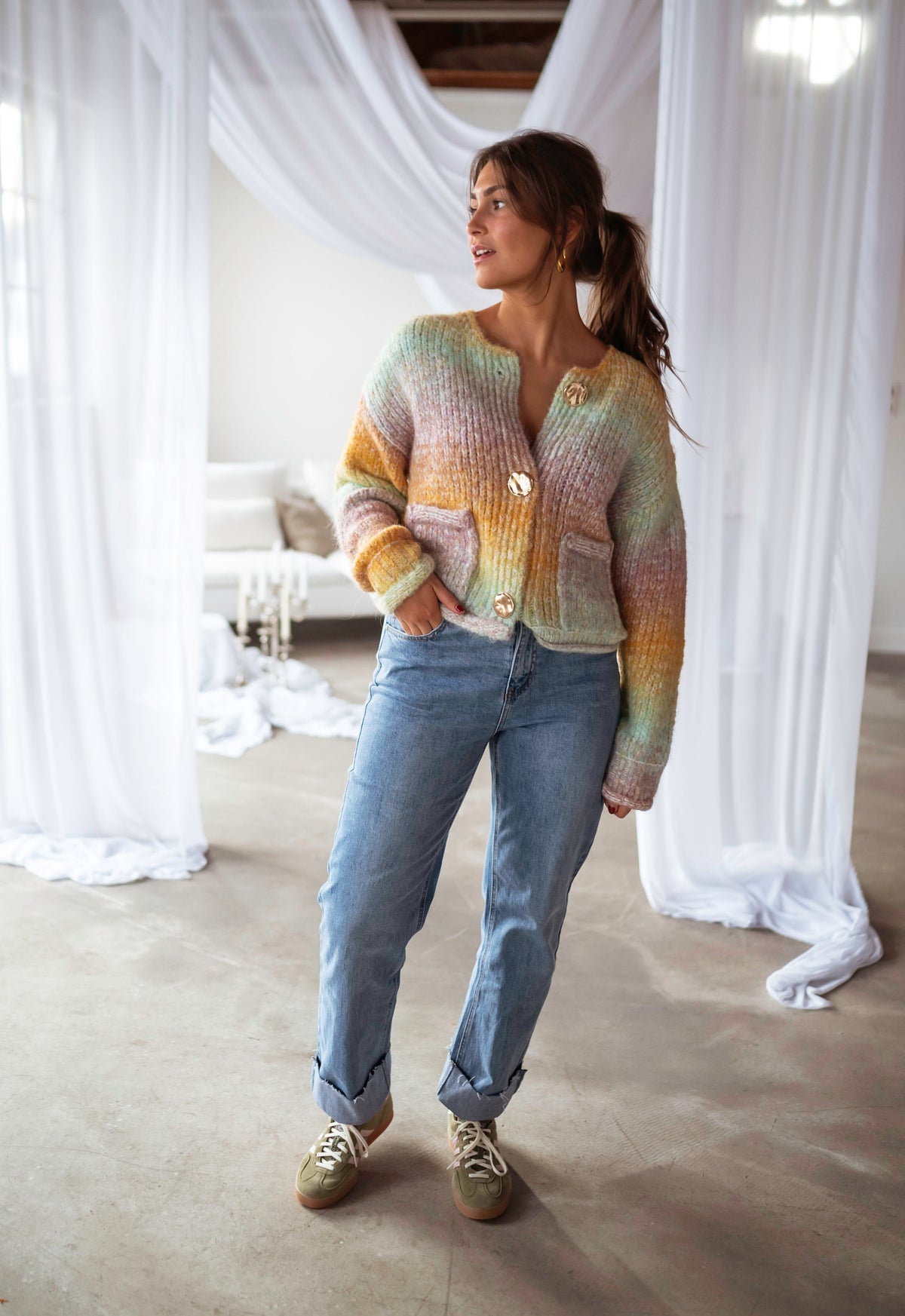 Gilet en maille tie-dye porté par une femme, silhouette entière, jean bleu, voilages