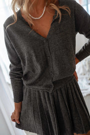 Gilet à boutons amovibles gris porté par une femme, vue rapprochée, jupe plissée, collier