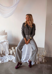 Gilet à boutons amovibles gris porté par une femme, silhouette entière, pantalon gris, sol clair