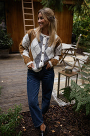 Gilet jacquard à col rond porté par une femme, vue de face, terrasse en bois, table basse