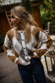 Gilet jacquard à col rond porté par une femme, vue de face, terrasse en bois, jean bleu