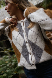 Gilet jacquard à col rond porté par une femme, vue rapprochée, losanges, boutons