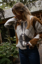 Gilet jacquard à col rond porté par une femme, vue de trois-quarts, cabane en bois, cheveux blonds