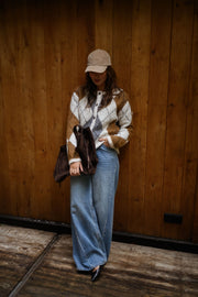 Gilet jacquard à col rond porté par une femme, vue de face, mur en bois, casquette