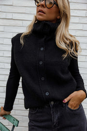 Gilet sans manches boutonné noir porté par une femme, vue de trois-quarts, main dans la poche, boutons