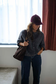 Gilet boutonné à col rond gris porté par une femme, vue de face, casquette bordeaux, sac marron