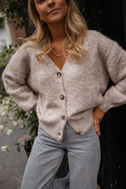 Gilet droit à col V taupe porté par une femme, vue rapprochée, boutons, jean gris