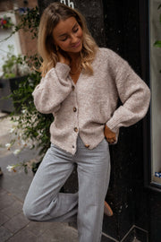 Gilet droit à col V taupe porté par une femme, vue de face, jean gris, vitrine noire