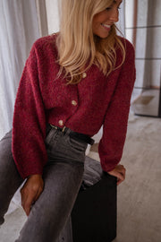 Gilet chiné boutonné bordeaux porté par une femme, vue rapprochée, boutons dorés, jean gris