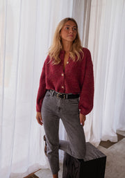 Gilet chiné boutonné bordeaux porté par une femme, vue de face, rideaux, jean gris