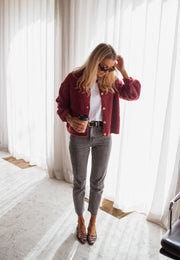 Gilet chiné boutonné bordeaux porté par une femme, silhouette entière, rideaux, escarpins