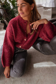 Gilet chiné boutonné bordeaux porté par une femme, assise, assise au sol, main sur le genou
