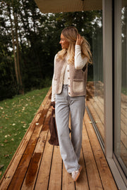Gilet effet mouton et daim taupe porté par une femme, silhouette entière, terrasse, jean