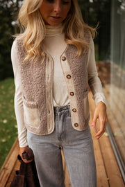 Gilet effet mouton et daim taupe porté par une femme, vue de face, col roulé, terrasse