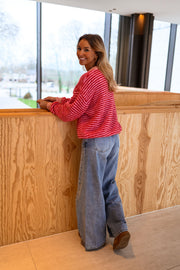 Gilet rayé à col rond porté par une femme, vue de face, comptoir en bois, jean clair