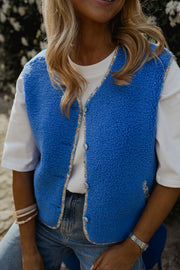 Gilet à bordures fleuries bleu porté par une femme, vue rapprochée, bracelets, t-shirt blanc