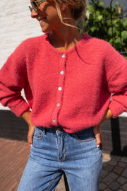 Gilet doux légèrement loose framboise porté par une femme, vue rapprochée, boutons, jean