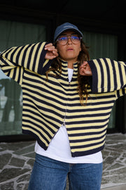 Gilet rayé à double zip porté par une femme, vue rapprochée, casquette, mains au col