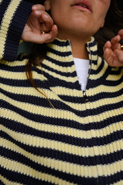 Gilet rayé à double zip porté par une femme, vue rapprochée, main près du visage