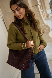 Gilet à col victorien porté par une femme, vue de trois-quarts, sac bordeaux, cheveux bruns