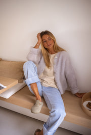 Gilet en kid mohair gris porté par une femme, assise, banc en bois, tête appuyée