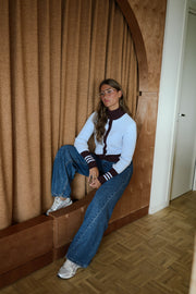 Gilet torsadé à col montant porté par une femme, assise, sur une banquette