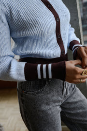 Gilet torsadé à col montant porté par une femme, gros plan de la manche rayée