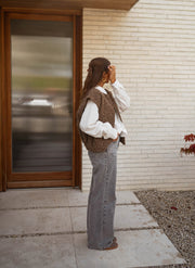 Gilet sans manches épais chocolat porté par une femme, vue de profil, porte, jean gris