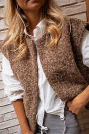 Gilet sans manches épais chocolat porté par une femme, vue rapprochée, bouclé, chemise blanche