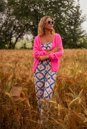 Gilet à col V boutonné rose porté par une femme, silhouette entière, champ de blé, lunettes