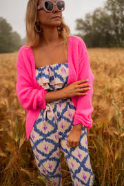 Gilet à col V boutonné rose porté par une femme, vue de face, lunettes, champ de blé