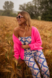 Gilet à col V boutonné rose porté par une femme, vue de profil, champ de blé, lunettes