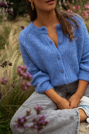 Gilet doux boutonné bleu porté par une femme, vue rapprochée, boutons, fleurs