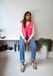 Gilet mouton sans manches rose porté par une femme, silhouette entière, jean bleu, étagère
