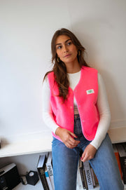 Gilet mouton sans manches rose porté par une femme, vue de trois-quarts, main sur la hanche, jean bleu