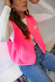 Gilet mouton sans manches rose porté par une femme, vue rapprochée, poche et col, mains sur la hanche