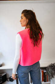 Gilet mouton sans manches rose porté par une femme, vue de dos, cheveux longs, jean bleu